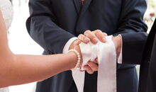 Zur Bestätigung der Vermählung legt Trauredner Markus Schäfler ein Band um die ineinandergelegten Hände des Brautpaares.