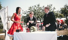 Braut und Bräutigam entzünden gemeinsam eine Kerze zum Gedenken an verstorbene Angehörige.